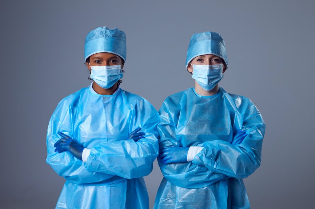 Studio Portrait Of Two Female Lab Research Workers In PPE